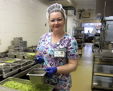 A Food Service Worker at Hogarth Riverview Manor prepares portions of modified texture lunch items.